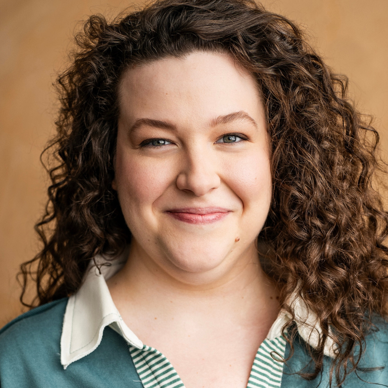 Portrait of Tristan Rose Gillia, actor at the American Shakespeare Center, with long brunette hair wearing a green top.